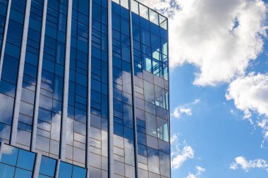 Bulutların yansıması olan yüksek katlı cam bir binanın yüzeyi..