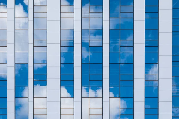 Bulutların yansıması olan yüksek katlı cam bir binanın yüzeyi. — Stok fotoğraf