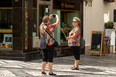 Portekiz 'de seyahat ederken eski şehrin sokaklarında selfie çeken iki kıdemli kadın. Aveiro, Portekiz - 19 Ağustos 2019