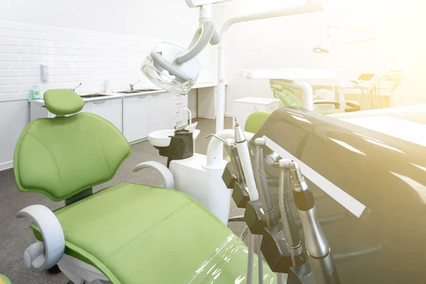 Green dental chair and equipment. Patient reception room in a modern medical center. Toned
