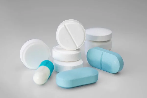 White and blue tablets and pills on a light background. Medical concept. Selective focus — Stock Photo, Image