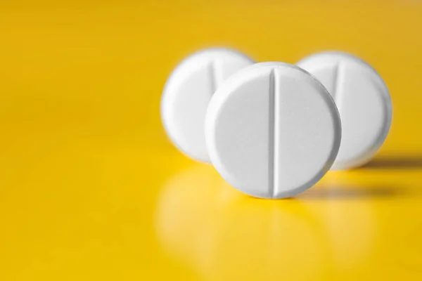 Three large white pill on a yellow background. Selective focus — Stock Photo, Image