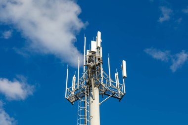 Telekomünikasyon kulesi 4G, 5G vericili. Telekomünikasyon kulesinde, bulutlu mavi gökyüzü üzerinde verici antenleri olan bir baz istasyonu..