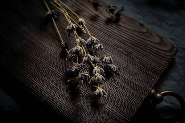 Flores secas de lavanda en la vieja tabla de cortar. Fondo oscuro para un diseño de tema culinario. — Foto de Stock