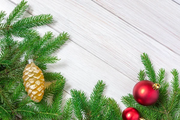 Navidad o año nuevo decoraciones fondo: ramas de abeto, juguetes rojos de Navidad en forma de bolas y cono de abeto de vidrio amarillo. Copiar espacio. — Foto de Stock