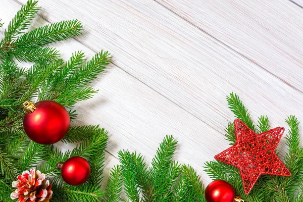 Noel ya da yeni yıl dekorasyonları: köknar dalları, balo şeklinde kırmızı Noel oyuncakları ve büyük yıldız. Boşluğu kopyala.