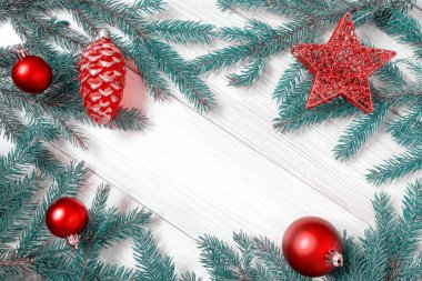 Noel ya da yeni yıl dekorasyonları: ağaç dalları, beyaz tahta üzerinde kırmızı Noel oyuncakları. Uzayı kopyala Renkli