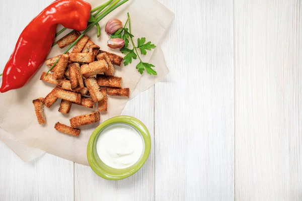 Slices of fried croutons with sour cream sauce, red pepper and garlic cloves close up on a white wooden boards. Top view with copy space — Stock Image Slices Fried Croutons Sour Cream Sauce Red Pepper Garlic Cloves Royalty Free Stock Photos