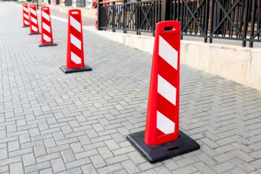 Dairelerin dışındaki yolda kırmızı ve beyaz bir sıra park yeri var..
