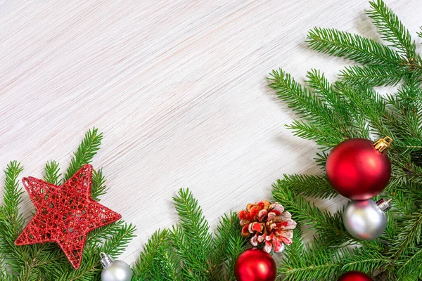 Christmas background. New year frame made of fir branches and red christmas toys on white wood board. Flat lay, Copy space. — Stock Photo, Image