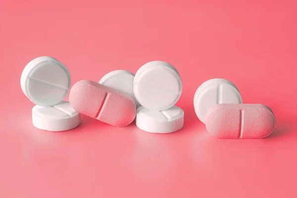 Kırmızı arka planda beyaz ve pembe haplar. Kilo kaybı ürünleri, vitaminler, hormonlar veya yatıştırıcılar, kadınların sağlık konsepti. Yakın çekim, seçici odaklanma.