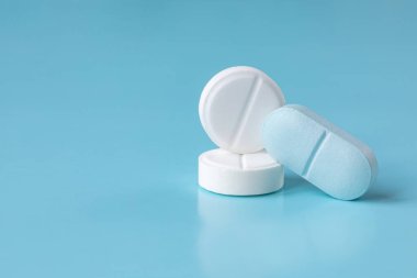 Beyaz ve mavi haplar ve hafif arka planda haplar. Tıbbi konsept. Yakın plan, seçici odaklanma. Boşluğu kopyala