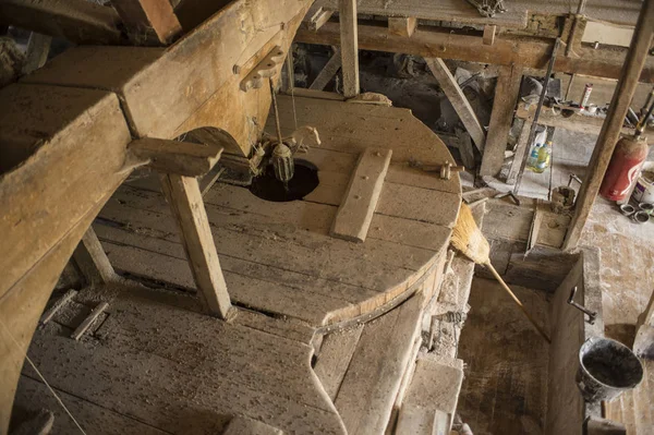 Traditional circular wooden flour mill equipment, viewed from top, with flour mill tools on floor below