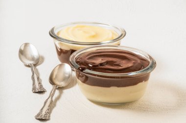 Vanilyalı ve çikolatalı puding bir cam kase beyaz zemin üzerine, kopya alanı