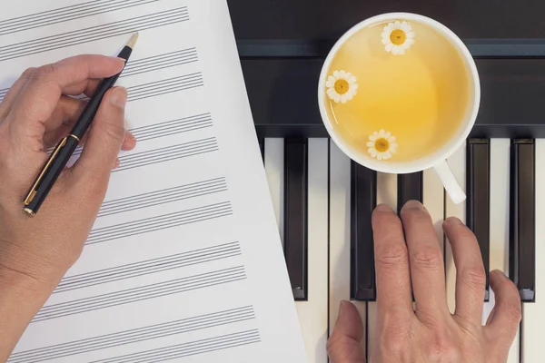 Clavier pour piano, mains et tasse de thé à la camomille . — Photo