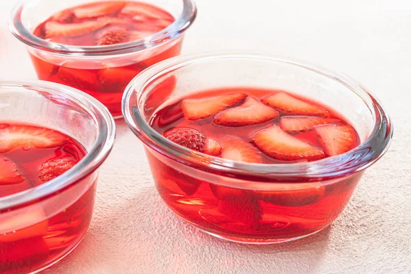 Strawberry Jelly in a Glass Bowls, Sliced Strawberries on a Chopping Board, Close Up, on White Background