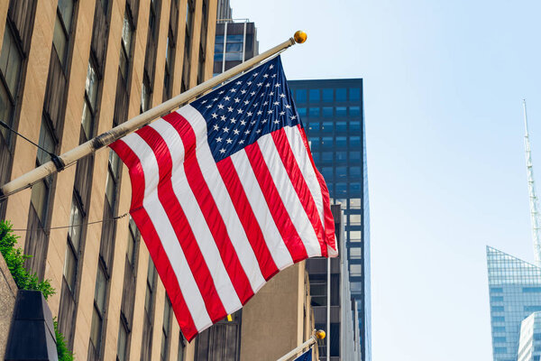 Небоскрёбы Нью-Йорка и американский флаг против чистого голубого неба
