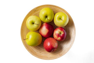 Elmalar tabakta. Tahta bir tabakta taze organik kırmızı ve sarı elmalar, yakın plan, beyaz arka plan, üst görüş