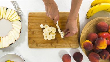 Beyaz arka planda doğranmış muz dilimleri, kadın elleri. Taze Meyve Tabağı