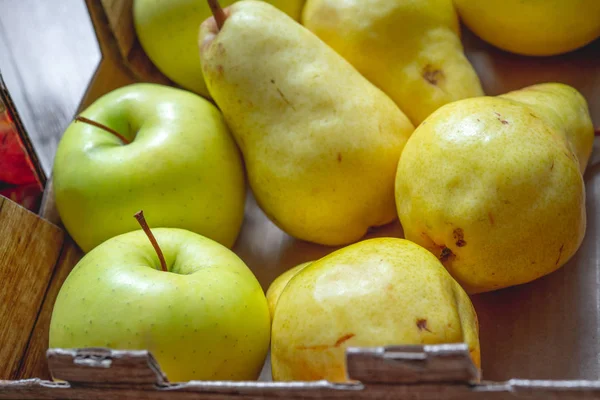 Pears and Apples, Autumn harvest. Green apples and yellow pears in a box close up.