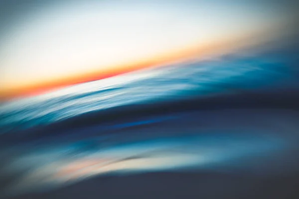 Abstract seascape with blurred panning motion. Before sunrise. Blue sea waves and sun on a horizon