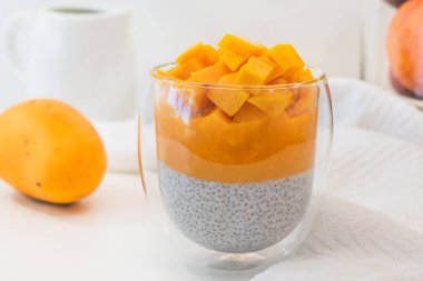 Mango Chia seed layered pudding smoothie close up on white background. Vegan healthy breakfast, dessert