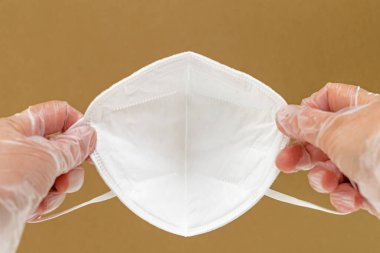 KN-95 koruma maskesi tutan vinil eldiven giyen kadın eller. Yakın çekim, kopyalama alanı. Virüs ve salgın hastalığın yayılmasını önleme, koruyucu ekipman konsepti