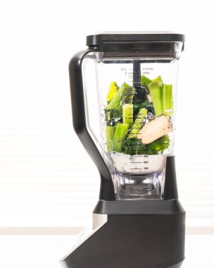 İçindekilerle karıştırıcı beyaz arkaplanı kapatıyor. Kereviz ıspanaklı muzlu smoothie tarifi.