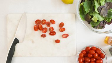 Kesme tahtasındaki vişneli domatesler düzdü. Domates tarifli marul salatası.