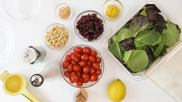 Marul salatası, kiraz domatesleri, kuru kızılcık, fındık ve mutfak masasına yakın ballı hardal salatası sosu malzemesi..