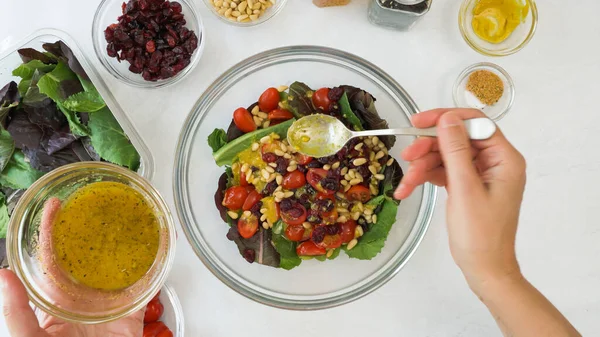 Çeri domatesli taze marul salatası, kuru kızılcık, fındık ve ev yapımı ballı hardal salatası sosu. Yakından bak, kadın eli.
