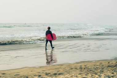 Morro Körfezi Eyalet Parkı, Kaliforniya / ABD - 13 Eylül 2020. Sahilde sörf tahtası olan bir sörfçü. Morro Körfezi, Kaliforniya
