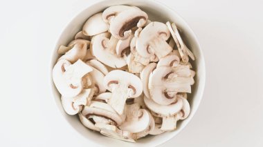 Bir kase taze, doğranmış mantar. Kırışık arka planda, düz bir zemine yakın.