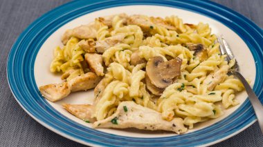 Mantarlı makarna, tavuk eti ve Alfredo sosu tabağa yakın.