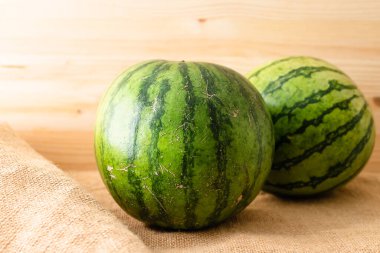 Karpuz yaklaştır. Kırsal ahşap arka planda iki olgun organik karpuz.