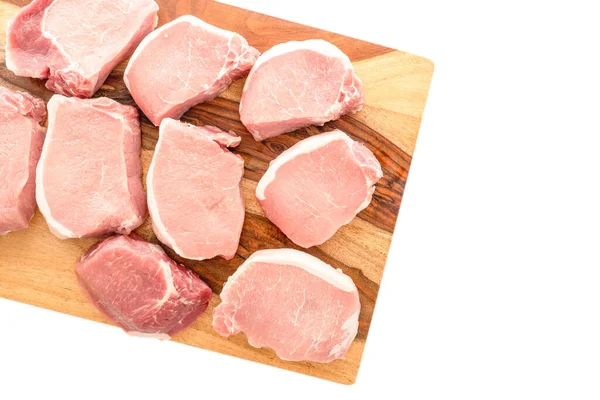 Boneless raw pork loin chops close up on wooden cutting board on white background, flat lay, copy space