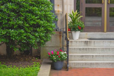 Siyah parmaklıkları ve saksısı olan taş merdivenler.