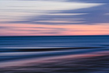 Yumuşak hareket bulanıklığı, deniz üzerinde günbatımının huzurlu geçişini yakalar..