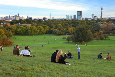 Gün batımında, Londra, İngiltere Primrose Hill'de oturan insanlar