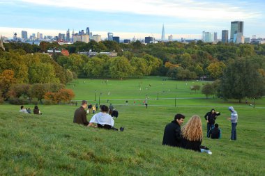 Gün batımında, Londra, İngiltere Primrose Hill'de oturan insanlar