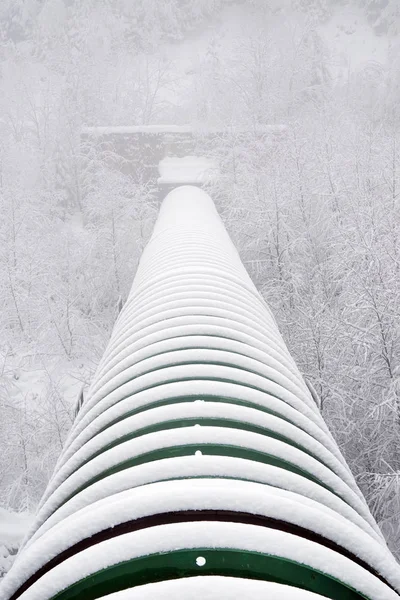 Industrial pipe over an alpine valley. Harsh winter conditions.