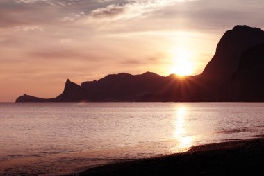 Karadeniz Sudak içinde güzel parlak sunset. Cape Kapchik ana hatları ile sahil. Crimea manzara.