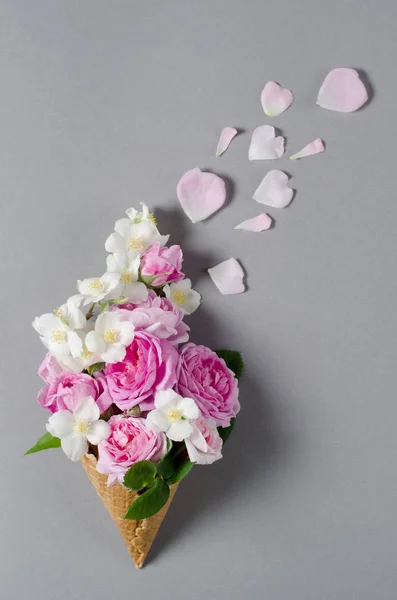 Čerstvé jarní růže v oplatkovém kornoutku. Krásné romantické pozadí v ploché laických stylu. — Stock fotografie