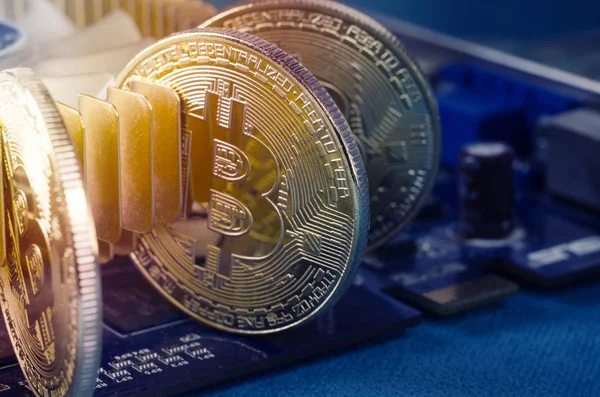 Moneda de Bitcoin de oro físico en una tarjeta de video de computadora. Nueva criptomoneda mundial independiente . — Foto de Stock