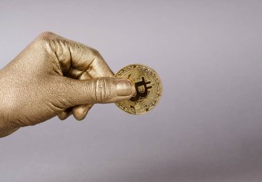 Cryptocurrency bitcoin fiziksel sikke altın el tutar.