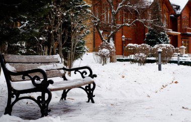 Winter park tarafından beyaz kar kaplı. Önünde park günlük ev ahşap Bank.