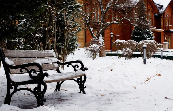 Winter park tarafından beyaz kar kaplı. Önünde park günlük ev ahşap Bank.