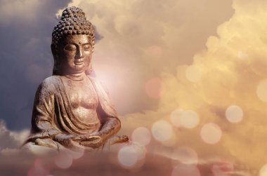 Meditasyon poz ile altın tonları bulutlar günbatımı gökyüzü karşı oturan Buda heykeli.