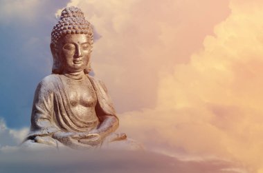 Meditasyon poz ile altın tonları bulutlar günbatımı gökyüzü karşı oturan Buda heykeli.