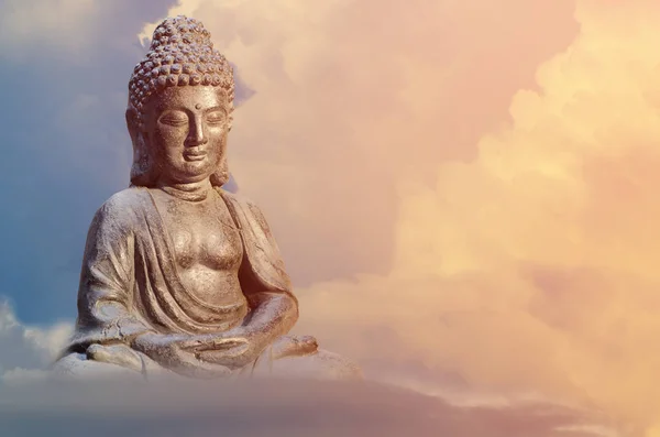 Statua di Buddha seduto in meditazione posa contro il cielo del tramonto con toni dorati nuvole . — Foto Stock
